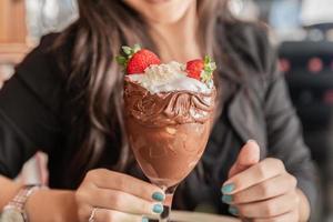 Eiscremeweiß mischt Erdbeere mit hohen Kalorien, kann Sie fett machen, weicher Fokus, verschwommen. leckerer Vanille- oder Schokoladeneisbecher mit Erdbeere.
