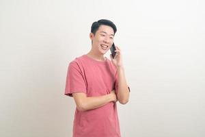 junger asiatischer mann, der smartphone und handy mit glücklichem gesicht verwendet oder spricht foto