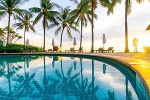 Sonnenschirm und Stuhl um den Pool im Hotelresort mit Sonnenaufgang am Morgen? foto