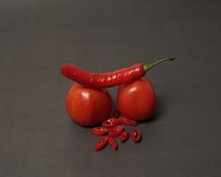 Die Kombination aus frischen Tomaten, roten Chilis und Eiern bildet ein lächelndes Gesicht. servierfertige Kochzutaten. Fokusunschärfe, Hintergrundinspiration. schwarze und rote Farbkombination. foto