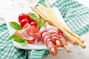 Grissini-Stäbchen mit Schinken, Tomate und Basilikum foto