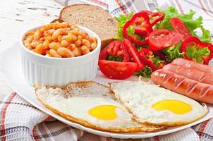 englisches Frühstück - Würstchen, Eier, Bohnen und Salat foto