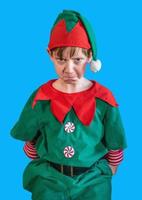 stirnrunzelnder Junge, der als Weihnachtself auf Bluescreen-Hintergrund verkleidet ist foto
