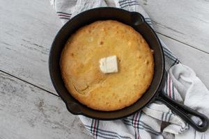 Gebackenes gelbes Maisbrot mit Butter in Draufsicht der gusseisernen Pfanne foto