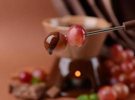 Schokoladenfondue mit Früchten, auf braunem Hintergrund