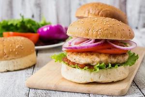 Sandwich mit Chicken Burger, Tomaten, roten Zwiebeln und Salat foto