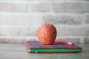 Schwarz zum Schulkonzept mit Apfel auf Notizblock auf dem Tisch. foto