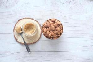 Mandelbutteraufstrich und Nüsse auf dem Tisch, Ansicht von oben foto