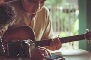 junger asiatischer mann, der gitarre spielt, die sich in einem café entspannt.