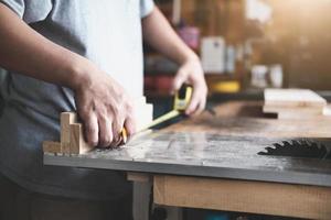 do-it-yourself-konzept handwerker verwenden ein maßband, um holzstücke zusammenzubauen, um holztische für kunden herzustellen. foto