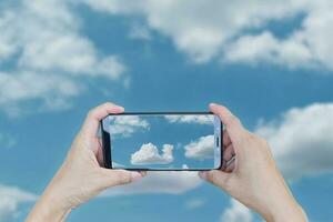 hand, die smartphone für die aufnahme hält, foto machen eine wolkenform ist ein hubschrauber am blauen himmel.