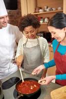 glückliche Frauen und Koch kochen in der Küche foto