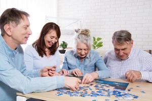 ältere familie mittleren alters sammelt puzzles am tisch im zimmer foto