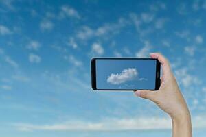 hand, die smartphone für die aufnahme hält, foto machen eine wolkenform ist ein hubschrauber am blauen himmel.