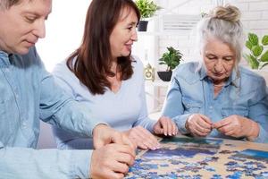 ältere familie mittleren alters sammelt puzzles am tisch im zimmer foto