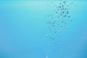 abstraktes Hintergrundbild von Blasen im Wasser. sauberes wasser mit wassertropfen und wellen. frisches wasser ein glas mit blasen blauem hintergrund. foto