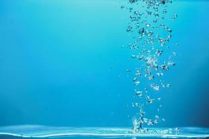 abstraktes Hintergrundbild von Blasen im Wasser. sauberes wasser mit wassertropfen und wellen. frisches wasser ein glas mit blasen blauem hintergrund. foto