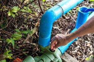 Nahaufnahme der Hand des Mannes zur Befestigung der Wasserpumpe Rohrströmungsausrüstung Landwirtschaft. Arbeiter Hände Klempnerarbeit Verbindungsrohr abschrauben, während Wasser austritt. Techniker, der das Wasserversorgungssystem überprüft. foto