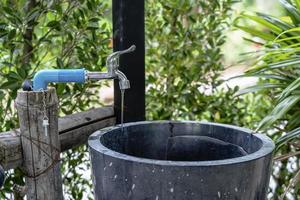 Nahaufnahme eines Wasserhahns oder eines undichten Wassertropfens mit grünem Hintergrund - Waschbecken im Badezimmer oder Park. Wasserspar- oder Sparkonzept foto