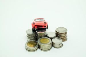 rotes Spielzeugauto und Baht-Münzen isoliert mit weißem Hintergrund. autoleasing, finanzierung, sparkonzept. foto