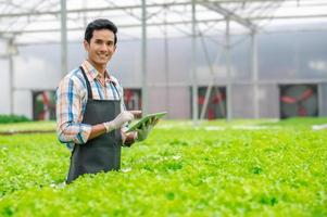 glücklicher asiatischer Bauer in der Hydroponik-Farm foto