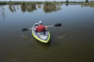 Junger Mann schwimmt auf dem Kajak auf dem Fluss foto