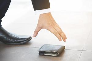 Nahaufnahme einer Person, die eine verlorene Brieftasche vom Boden aufhebt foto