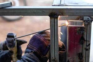 Nahaufnahme eines Arbeiters, der Handschuhe trägt und Metall schweißt. foto