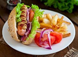 Hotdog mit Ketchup-Senf und Salat auf hölzernem Hintergrund. foto