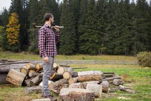 Yong-Männchen im Wald, das Holz mit Stahlaxt hackt, Landlandschaft mit Holzfäller foto