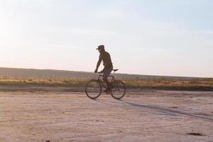 Alleinfahrer auf Rennrad mit festem Gang in der Wüste in der Nähe des Flusses, Bilder von Hipster-Touristenradfahrern. foto