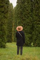 Frau mit Hut, die allein im schönen Herbstpark spazieren geht foto