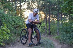 junger Sportler, der auf seinem professionellen Mountainbike oder Cyclocross-Fahrrad im Wald fährt foto