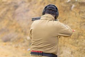 Männliches Training mit Pump-Action-Schrotflinte im Freien im Feld. foto