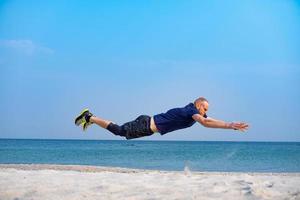 junger männlicher athlet, der an einem sonnigen tag am strand trainiert foto