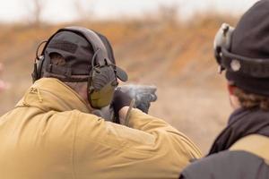 Männliches Training mit Pump-Action-Schrotflinte im Freien im Feld. foto