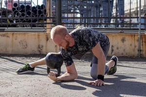 junges bärtiges männliches athletentraining im industriegebiet am sonnigen tag, kettlebells trainiert draußen, städtischer hintergrund foto