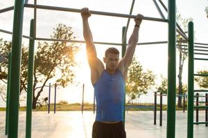muskulöser Mann, der Klimmzüge an der horizontalen Stange macht, morgens Training des starken Mannes im Fitnessstudio im Park im Freien. foto