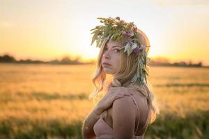 Porträts von jungen Frauen, die sich während des Sonnenuntergangs im Weizenfeld gut amüsieren, Dame im Kopfblumenkranz während foto