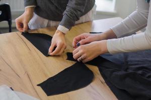 Näherin bei der Arbeit auf dem Tisch, Schneiderfrau arbeitet im Studio mit Kleidung foto