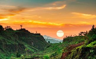 schöne naturlandschaft der bergkette mit sonnenunterganghimmel und wolken. Gebirgstal in Thailand. Landschaft der Bergschicht in der Abenddämmerung. Tropenwald. natürlichen Hintergrund. orange und goldener himmel.
