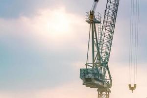 baukran gegen den blauen und rosa himmel. Immobilienwirtschaft. baukran verwendet rollenhebegeräte auf der baustelle. Kran zu vermieten. Kranhandel für Bauunternehmen. foto