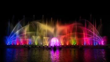 der bunte Springbrunnen tanzt zur Feier des Jahres mit dunklem Nachthimmelhintergrund. foto