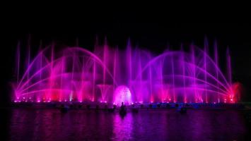 der bunte Springbrunnen tanzt zur Feier des Jahres mit dunklem Nachthimmelhintergrund. foto