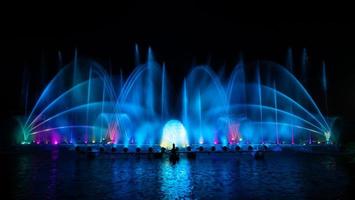 der bunte Springbrunnen tanzt zur Feier des Jahres mit dunklem Nachthimmelhintergrund. foto