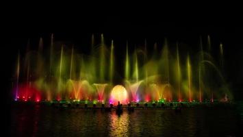 der bunte Springbrunnen tanzt zur Feier des Jahres mit dunklem Nachthimmelhintergrund. foto