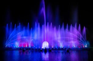 der bunte Springbrunnen tanzt zur Feier des Jahres mit dunklem Nachthimmelhintergrund. foto