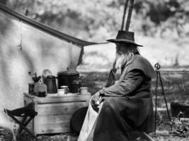 Ein älterer Cowboy saß mit einer Waffe da, um die Sicherheit des Lagers im westlichen Bereich zu bewachen foto