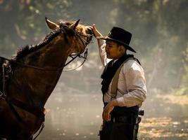 Ein junger Cowboy ruhte sich mit einem Pferd im Bach aus, nachdem er das Pferd geduscht hatte foto