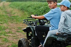 Zwei Brüder, die ein Vierrad-ATV-Quad fahren. glückliche Kindermomente. foto